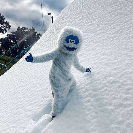 Snow Riders company mascot climbing a snowbank