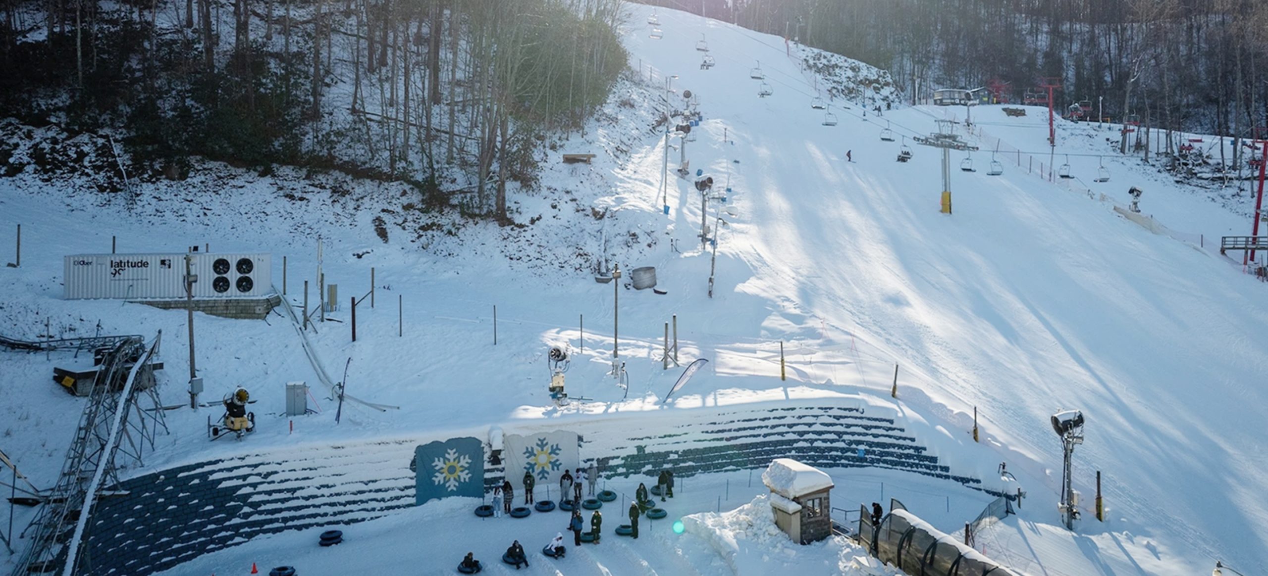 Overview of the Ober Mountain facilities with an L60 machine on the left and people waiting to ski down the slope in front of them.