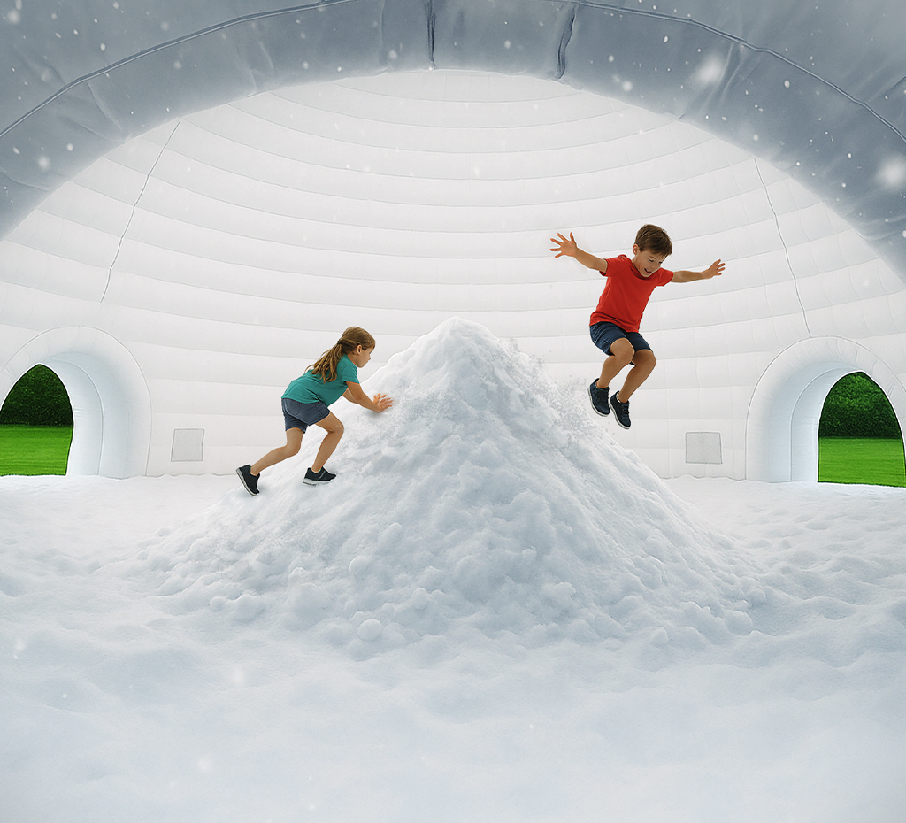 Children dressed in summer clothes playing on a snowbank inside an inflatable igloo