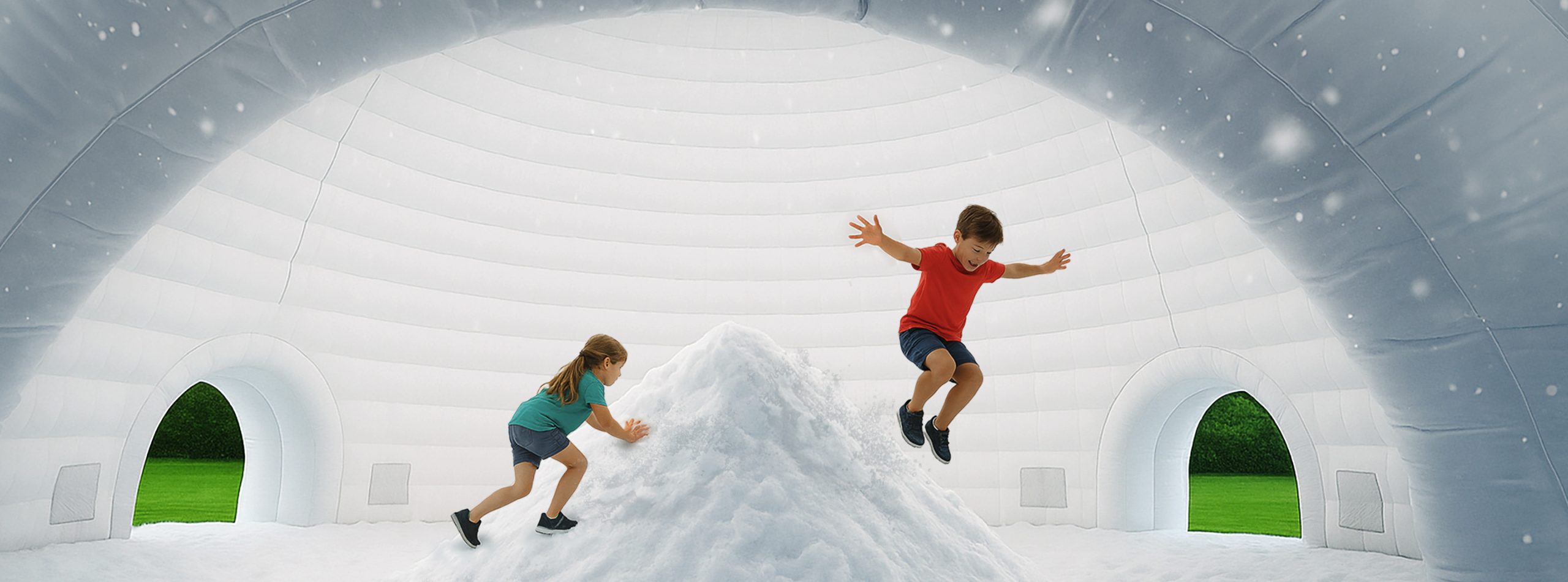 Children dressed in summer clothes playing on a snowbank inside an inflatable igloo